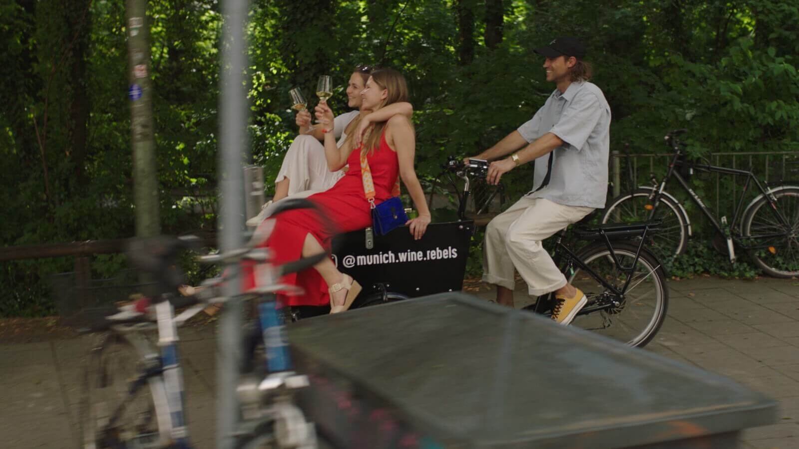 2 females sitting on wine bike with guy riding outdoor